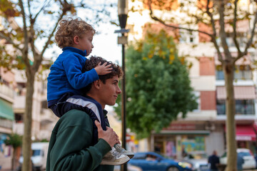 Older brother carrying toddler on shoulders, showing family bond and childhood joy outdoors