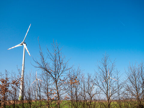 Wind turbines near highway road producing renewable electricity in rural landscape in Austria. Modern wind energy technology and infrastructure under clear blue sky.