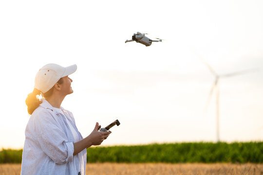 Farmer flying drone in field with wind turbines for smart farming