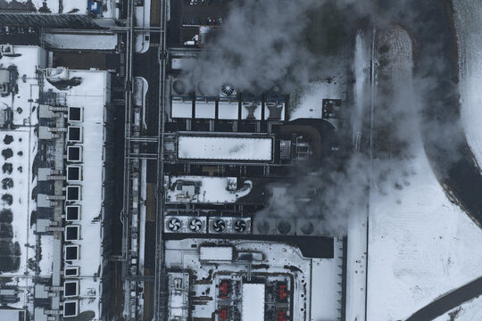Aerial view of large data center complex featuring cooling towers emitting steam on a snowy winter day, Eemshaven, Netherlands.