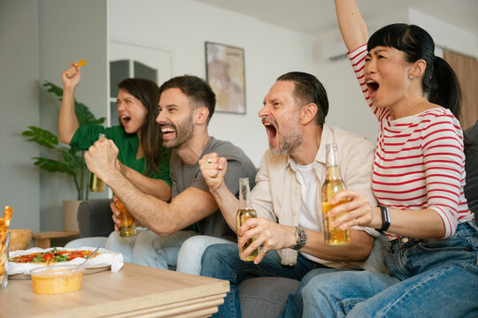 Friends celebrating while watching football match at home