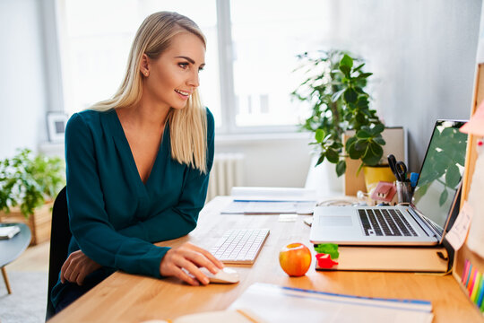 Caucasian woman in 30s using laptop at home office desk
