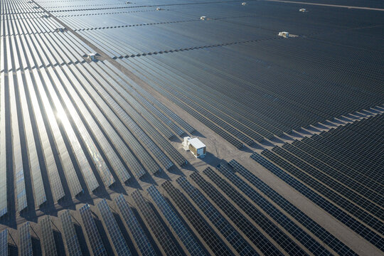 Aerial view of solar panels stretch across the arid landscape, reflecting the sun's intense glare in rhythmic patterns, Searchlight, Nevada, United States.