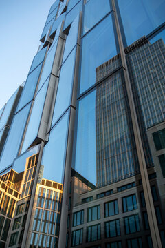 Architecture of a corporate skyscraper where blue glass facade holds reflections and vertical structure is seen in dramatic perspective