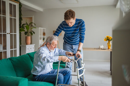 Caregiver assisting senior man with walker at home