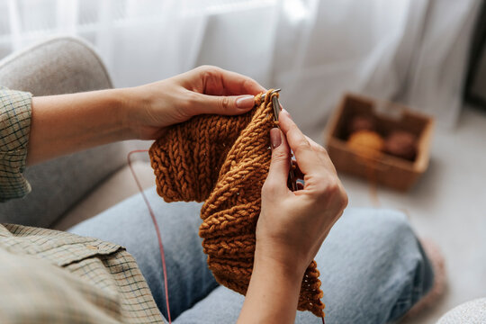 Close up of hands knitting a cozy handmade wool textile indoors