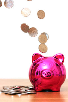 Pink piggy bank with money falling into it