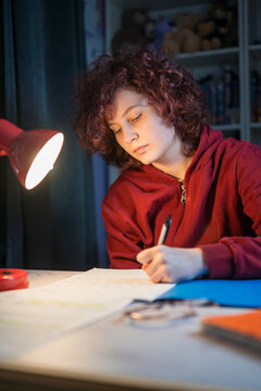 Student studying at night with desk lamp focusing on exam preparation