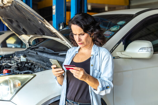 Woman customer standing in front of auto repair service shop receive car key, holding credit card cashless payment for insurance claim in modern small business garage, female mechanic garage owner