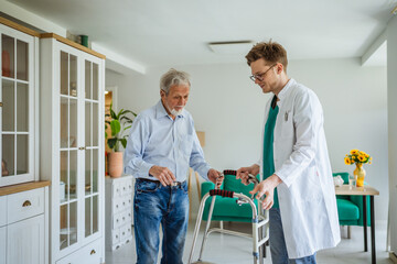 Fototapeta premium Healthcare professional assisting senior man using walker at home