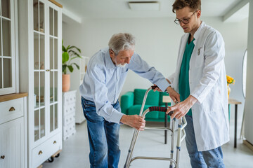 Elder man receiving assistance for rehabilitation with walker
