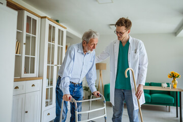 Healthcare worker assisting senior man with walking frame
