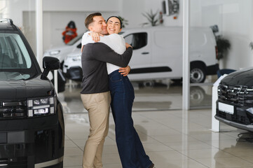 Portrait of a beautiful young couple choosing a new car at a car dealership
