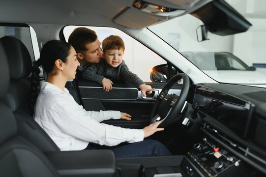 Family in a car dealership. Happy family choosing a new car in a showroom