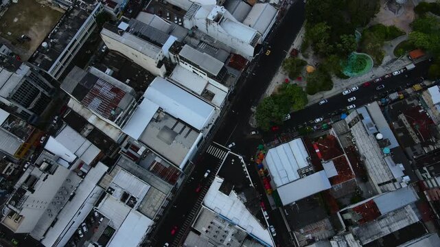 Downward aerial over city buildings in Manaus, Brazil tilting upward to show the urban extent during late afternoon. Recorded in 4K Apple ProRes 422.