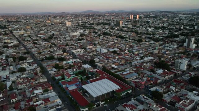Wide aerial recede looking at the full extent of Guadalajara city and a distant hill horizon after sunset. Shot on 4K Apple ProRes 422.