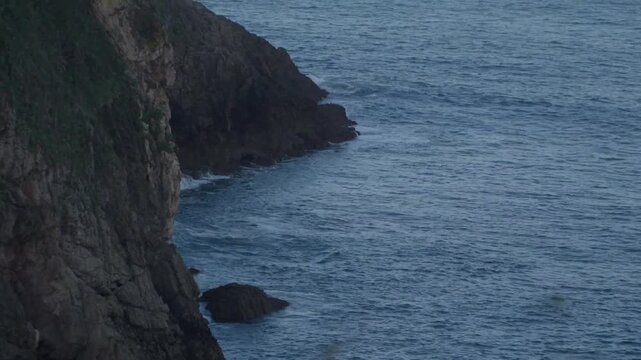 Ocean waves gently moving along steep rocky cliffs on the coastline of Cand&aacute;s, Asturias, Spain. Natural Atlantic seascape with rugged rocks and deep blue water along the northern Spanish coast.