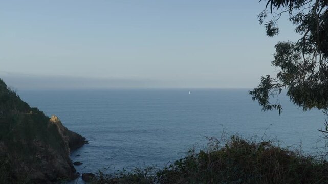 Scenic ocean view from coastal cliffs in Cand&aacute;s Asturias, Spain. Calm waters of the Cantabrian Sea stretch to the horizon with a small sailboat visible in the distance along northern Spain&rsquo;s coastline