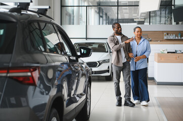 Couple choosing new car in dealership showroom