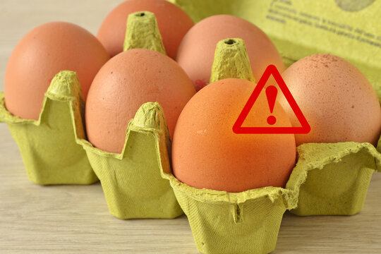 Warning sign on eggs in carton box - Concept of salmonella infection risk, bacterial contamination and health problems