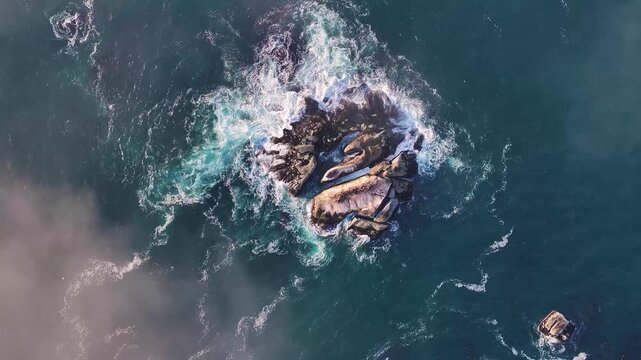 Aerial view of the dark, rugged rocks clashing against the turquoise ocean, creating a mesmerizing dance of power and serenity, Cape Town, Western Cape, South Africa.