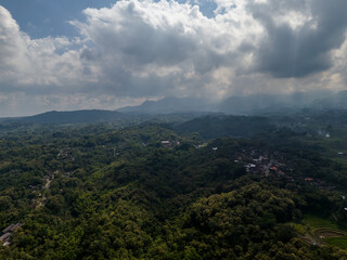 Fototapeta premium Dramatic sun rays breaking through clouds over the misty valley of Mount Lawu slopes.