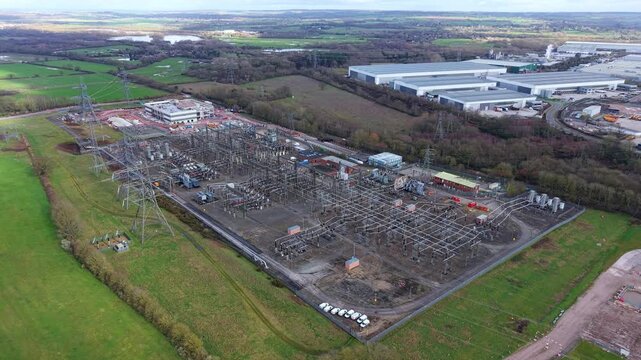 Aerial view of the National Grid Hams Hall Substation with its intricate network of power lines and equipment amidst the lush green fields, Birmingham, United Kingdom.
