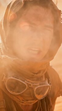 Post apocalyptic survivor struggling in a fierce desert sandstorm. Man with dirty face coughing as strong wind blows dust and sand. Dystopian wasteland concept in slow motion
