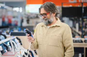 Mature man examining beard trimmer in electronics store