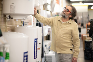 Mature man choosing water heater in appliance store