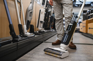 Man trying cordless vacuum cleaner in appliance store © Serhii