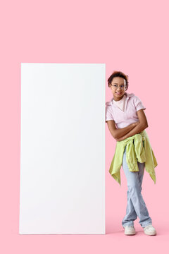 Teenage African-American girl with blank poster on pink background