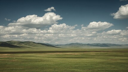Obraz premium Serene Green Landscape Under a Vast Sky with Fluffy Clouds and Gentle Rolling Hills in Natural Daylight