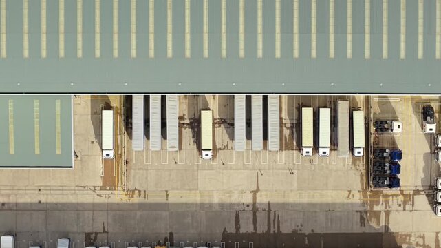 Aerial view of cargo trucks lined up next to the warehouse, creating a rhythmic pattern of textures and tones, Birmingham, England, United Kingdom.