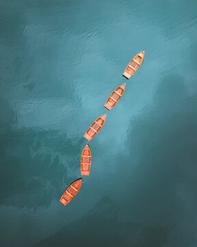 Aerial view of boats lined up on the blue water of Lake Braies, creating a striking contrast of colors, Braies, Trentino-South Tyrol, Italy.