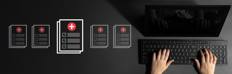 A professional workspace with hands typing on a keyboard, surrounded by medical forms and...