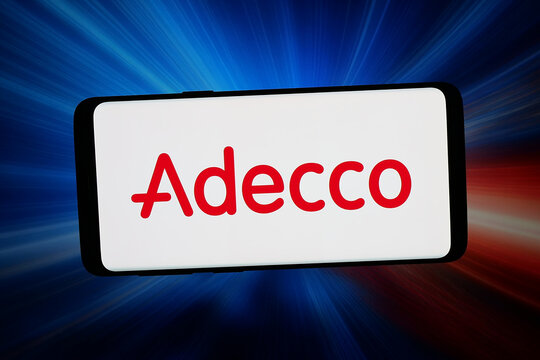 Stuttgart, Germany - 03-13-2026: In this photo illustration, the logo of HR and staffing company The Adecco Group is displayed on a smartphone in front of abstract background on computer screen.