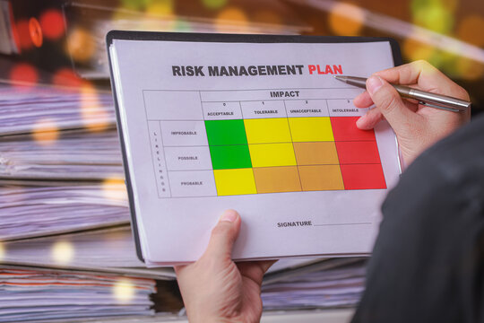 Focused professional evaluating risk priority and conducting careful business analysis using detailed management plan document matrix