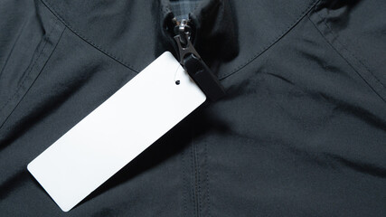 Close-up of black jacket zipper with blank white price tag for retail © Andik