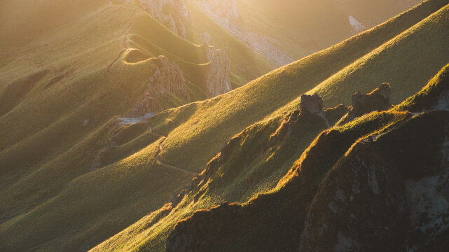 View of golden light cascading over the lush, rolling hills and rugged peaks creating a breathtaking scene of natural beauty, Mont-Dore, Auvergne-Rhone-Alpes, France.