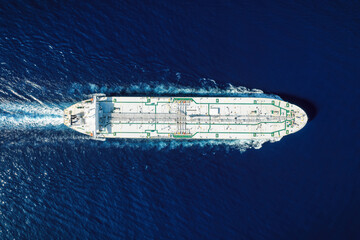 Obraz premium High aerial top view of a crude oil tanker traveling with speed over the ocean with copy space