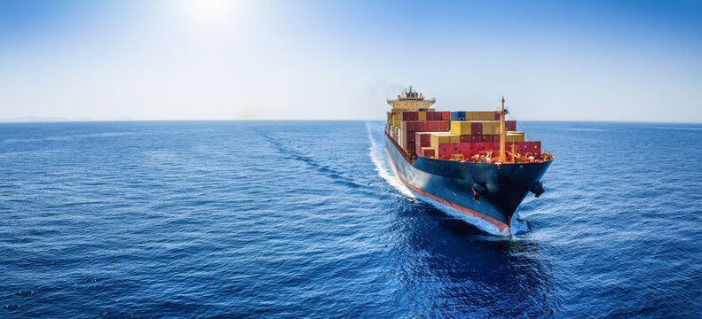 Panoramic front view of a cargo ship carrying containers for import and export, business logistic and transportation in open sea with copy space