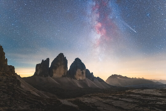 View of the iconic Tre Cime di Lavaredo peaks stand majestically under a starlit sky with the Milky Way's vibrant colors, Auronzo di Cadore, Veneto, Italy.