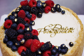 Cake with colorful berries and a decorative inscription on top