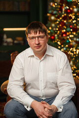 Man sitting in front of a Christmas tree with lights at home