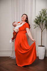 Mother holds baby while posing in bright dress indoors