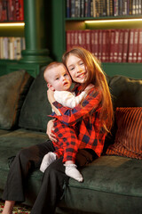 Child holds baby on green couch in cozy indoor setting during daytime