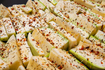 close up of zucchini sticks seasoned with herbs and spices, ready for cooking