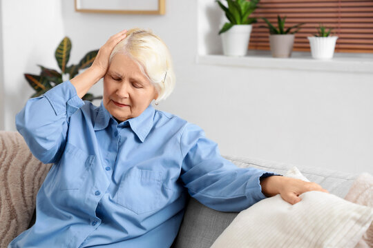 Senior woman on sofa suffering from loud neighbours at home