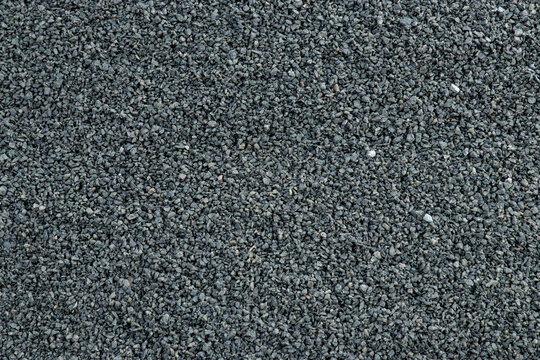 Close-up view of dark gray gravel texture with small stones and pebbles, suitable for construction, landscaping, or decorative purposes in various outdoor projects